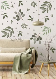 a living room with a white couch and green leaves on the wall