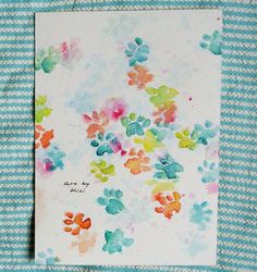 a card with colorful flowers on it sitting on top of a blue and white striped cloth