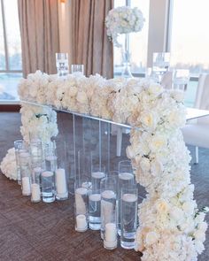 white flowers and candles are arranged on the floor in front of a mirror at a wedding reception