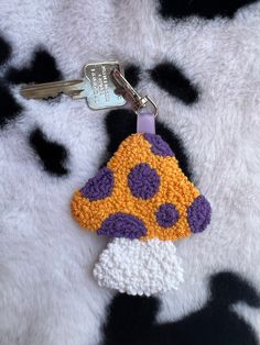 a crocheted keychain with a yellow and purple hat on it's side