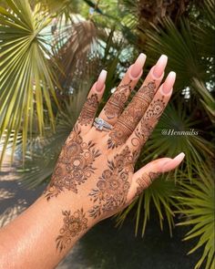 a woman's hand with henna on it and palm trees in the background