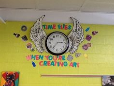 there is a clock on the wall with some pictures and magnets around it that says time flies when you're creating art