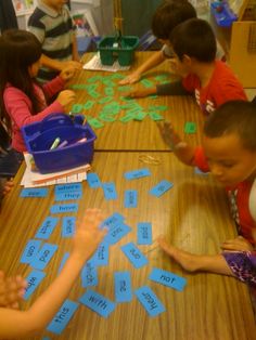 several children are sitting at a table with sticky notes on it and one child is pointing to them