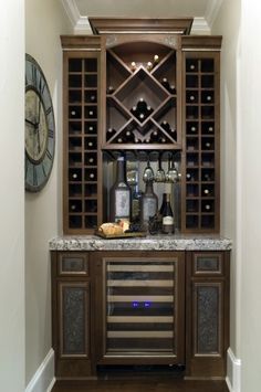 a wine rack with bottles and glasses on it in the corner of a room next to a clock