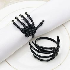 black skeleton hand napkin rings sitting on top of a white plate