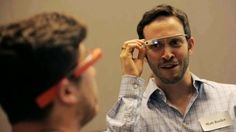 a man is looking at another man with google glass on his head while he looks into the mirror