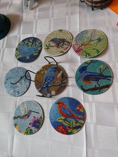 six coasters with colorful birds on them sitting on a white tablecloth covered floor