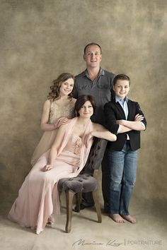 a family posing for a portrait in front of a brown background with their arms around each other