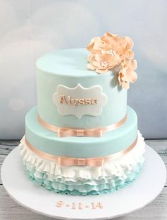 a three tiered blue and white cake with flowers on the top is sitting on a plate