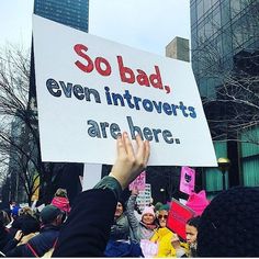 a person holding up a sign that says so bad even introverts are here