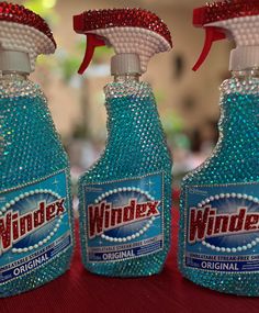 three bottles of windex on a table with red and white trimmings,