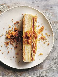 a white plate topped with a piece of cake covered in crumbled toppings