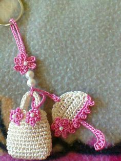 two crocheted purses are hanging from a keychain on the carpet