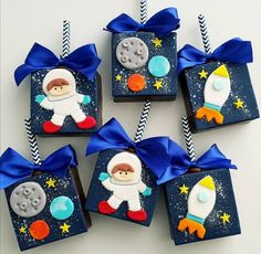 four little boxes decorated with space related items and blue ribbon tied around the top one has an astronaut on it