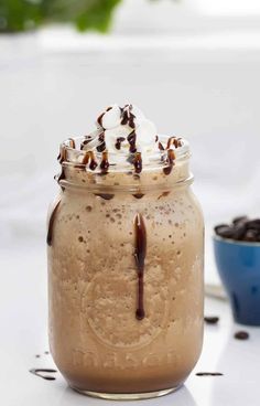 a glass jar filled with chocolate pudding and whipped cream on top of a white table