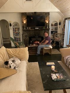 a woman sitting in a living room with a dog on the couch and coffee table