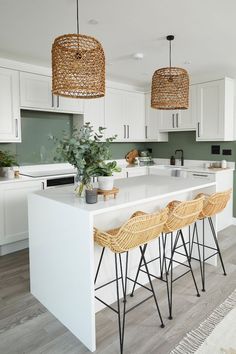 a kitchen with white counter tops and wicker stools next to an island in the middle