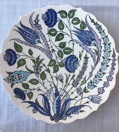 a white plate with blue flowers and leaves on the bottom is shown in an instagramt