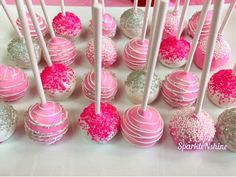 pink and white cake pops with sprinkles are arranged on a table top