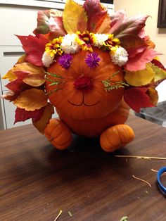 a pumpkin decorated with flowers and leaves on top of a table next to a pair of scissors