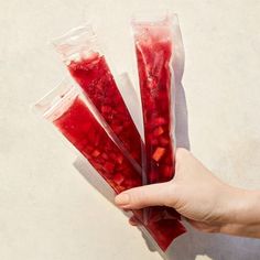 a person holding three bags of food in one hand and the other two are filled with red liquid