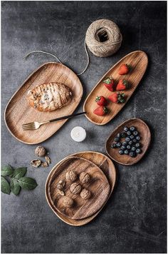 three wooden trays filled with food on top of a black table next to a spool of twine