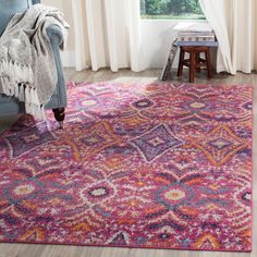 a living room area with a purple rug and blue chair in front of the window