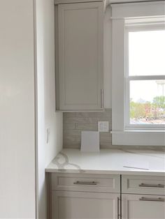 an empty kitchen with white cabinets and counter tops