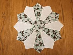 a white and green flower with pinecones on it sitting on a wooden table