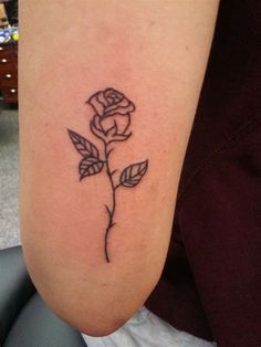 a small rose tattoo on the arm