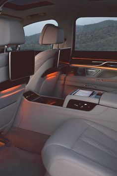 the interior of a luxury car with its lights on and electronic controls in the passenger seat