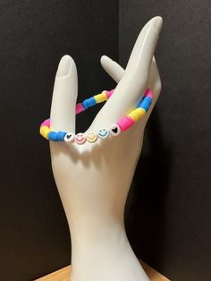 a white mannequin head with colorful bracelets on it's fingers and eyes