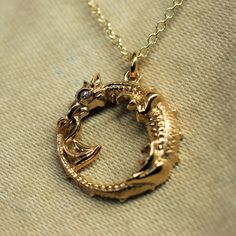 This piece will be hand made for you in the United Kingdom. Please allow up to 30 days for it to be completed. Gold ouroboros dragon pendant and chain.Originating in Ancient Egyptian iconography, the ouroboros entered western tradition via Greek magical tradition and was adopted as a powerful symbol in Norse Viking mythology.This round Ouroboros Dragon pendant is made from 9ct gold that has been given a high-carat gold coating. It has an eye made from a bright, brilliant cut diamond.The dragon measures 1.9cm (which is around three quarters of an inch). The gold dragon has been hung from a strong but elegant, 18 inch long solid gold chain. It has been given a Hallmark from the Assay Office to prove that it is made of gold.To create this piece I have utilized some of the most up-to-date tech Ouroboros Necklace, Ouroboros Dragon, Viking Mythology, The Ouroboros, Vintage Dragon, Gold Dragon, Norse Vikings, Dragon Necklace, Diamond Eyes