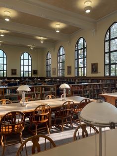 an empty library with tables and chairs in front of two large windows filled with books