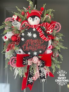 a christmas wreath with a penguin and candy canes hanging on the front door,