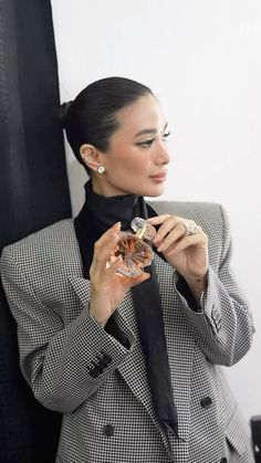 a woman wearing a black and white checkered suit holding a piece of jewelry in her hands