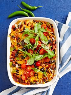 a casserole dish with tomatoes, black olives and spinach on top