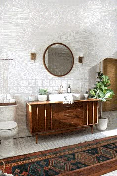 a bathroom vanity with a mirror above it and a rug on the floor next to it