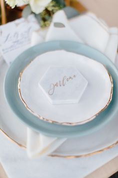 a table setting with plates, napkins and place cards on top of each plate