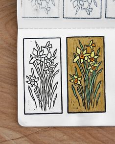 an open notebook with drawings of flowers and leaves on the cover, sitting on a wooden surface