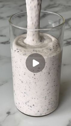 a glass filled with liquid sitting on top of a marble counter next to a white object