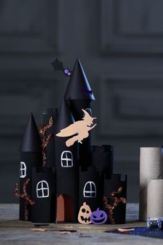 a castle made out of black paper with decorations on the front and side, sitting next to a roll of toilet paper