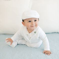 A baby boy in the Elijah 3-Piece Suit and cap is sitting on a light blue blanket. The outfit, perfect for a special occasion, features textured cotton. He has a slight smile and is looking slightly upward, with white pillows in the background. Baby Boy Formal Wear, Handsome Outfit, Baby Boy Christening Outfit, Boy Dress, Baby Boy Christening, Baby Boy Dress, Style Pant, Christening Outfit