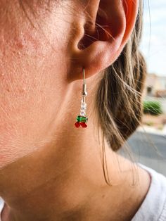 a close up of a person wearing some kind of red and green earring on their ear