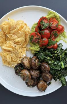 a white plate topped with potatoes, spinach and other food items on top of it