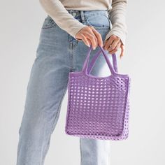 a woman is holding a purple bag in her hands