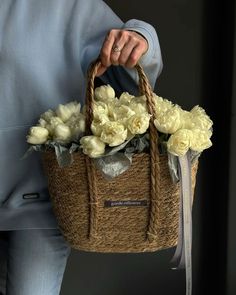 a person holding a basket with flowers in it