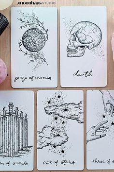 four cards with ink drawings on them sitting on a table next to some donuts