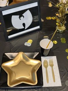 a black table topped with gold plates and silverware next to a star shaped plate