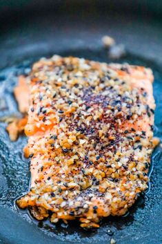 a piece of salmon with seasoning on it sitting in a skillet, ready to be cooked